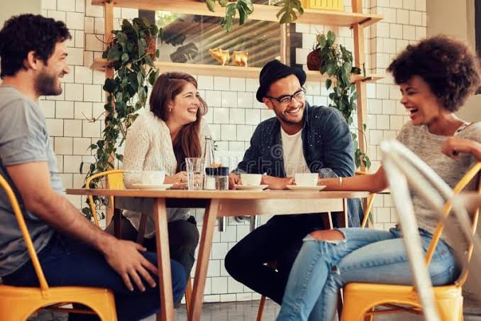 A cafe photo of four friends with the original tiled-wall background still in place, before background removal
